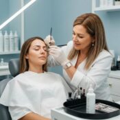 Brow specialist gently working on a client's eyebrows in a salon, showing popular semi-permanent enhancement techniques