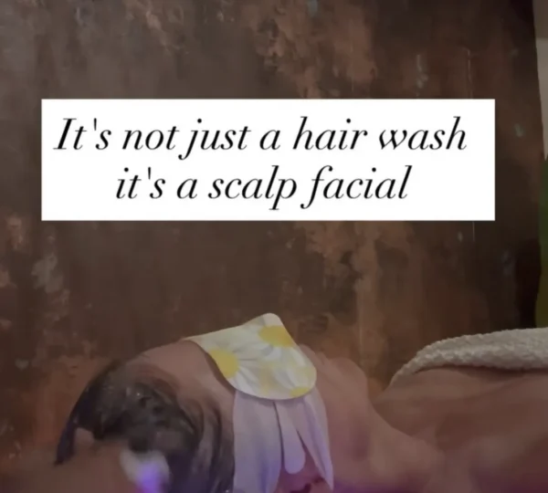 Person receiving a scalp treatment with eye pads, relaxing in a spa setting.