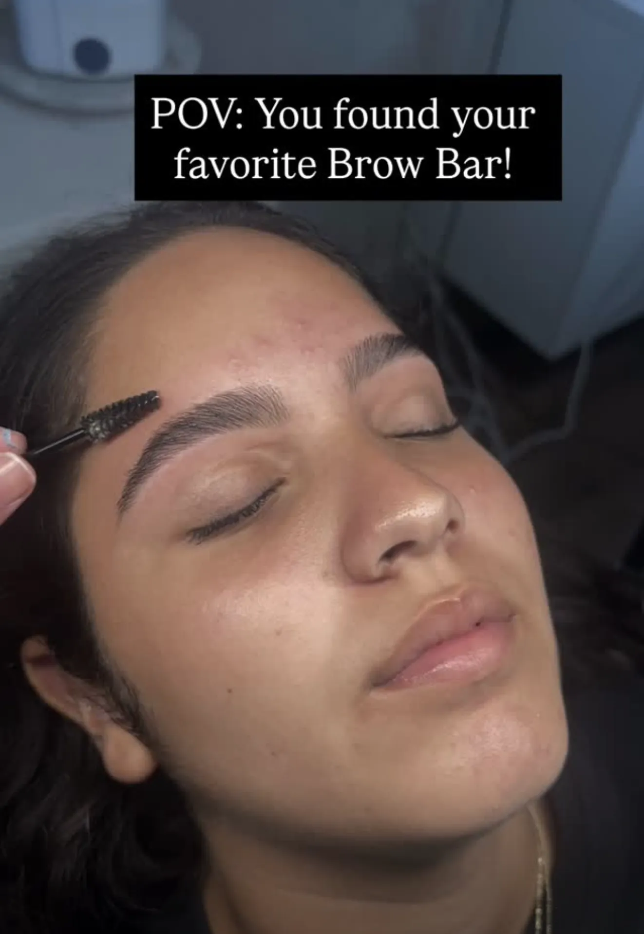Beauty professional shaping eyebrows with tweezers in a bright salon environment