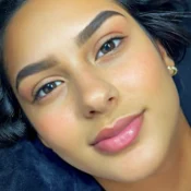 Young woman with natural makeup and defined eyebrows, looking directly at the camera.