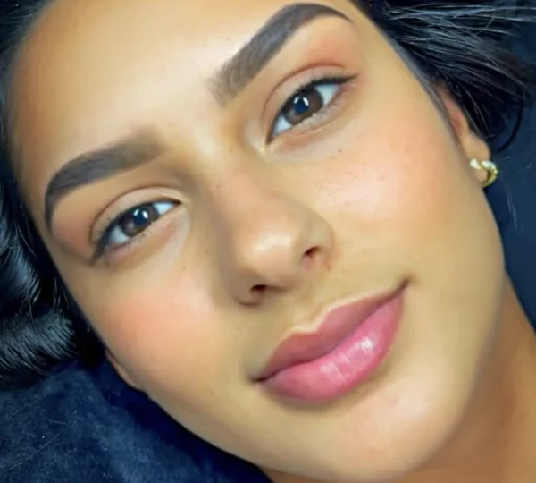 Young woman with natural makeup and defined eyebrows, looking directly at the camera.