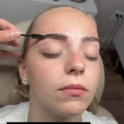 A person having their eyebrows groomed with a brush in a salon setting.